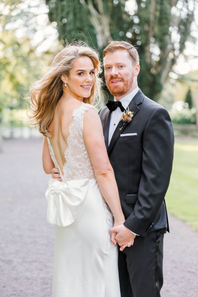 Bride and groom pose on pathway smiling