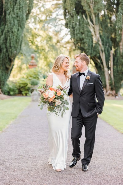 Bride and groom look at each other on pathway smiling