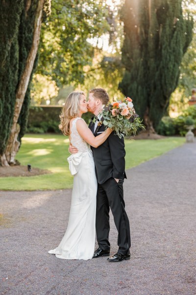 Bride and groom kiss kissing on pathway