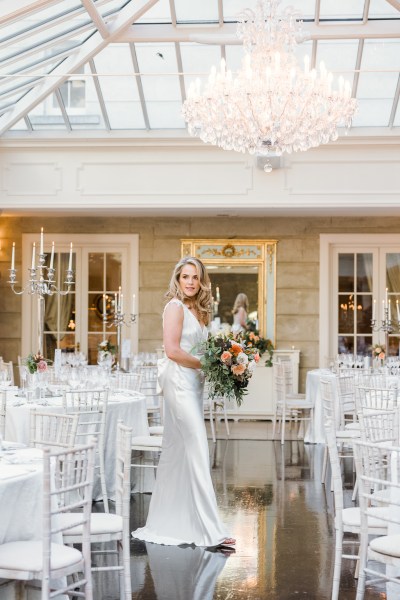 Bride stands inside dining room setting table and chairs