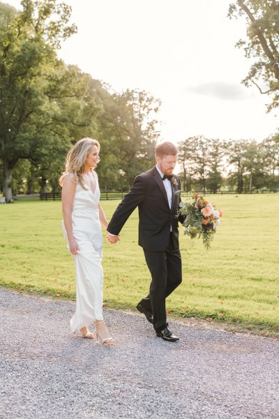 Bride and groom walk hand in hand on the pathway to wedding venue