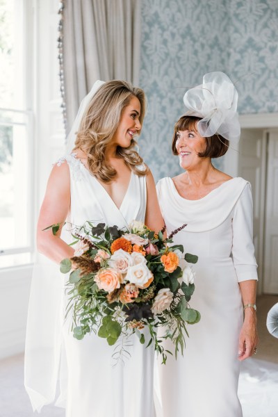 Bride looks at mother holding bouquet