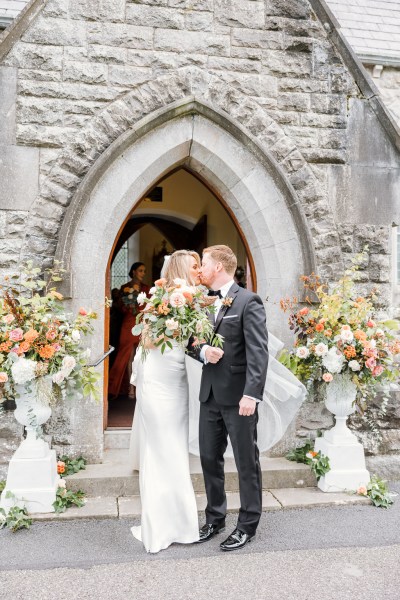 Bride and groom exit the church exterior kissing