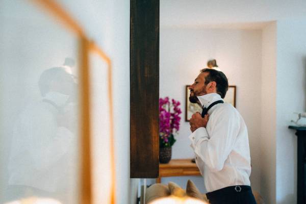 Groom looks in mirror as he gets ready