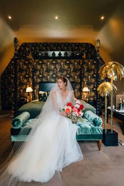 Bride sits on blue satin sofa interior room manor house