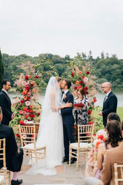 Bride and groom kissing at alter on the grass