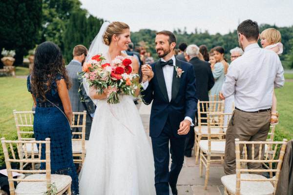 Bride and groom holding bouquet walking from ceremony