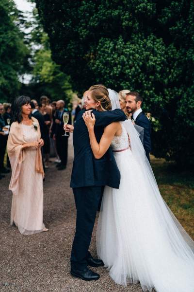 Father guest hugs bride with other guests in shot