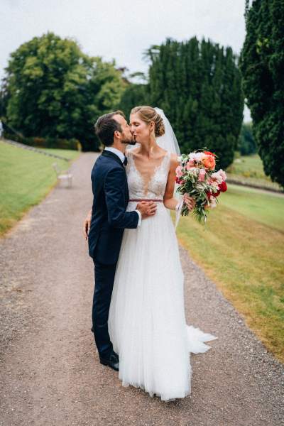 Bride and groom kiss on the pathway flowers in shot