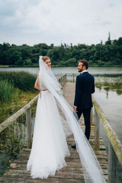 Bride and groom walk along the boardwalk on lake