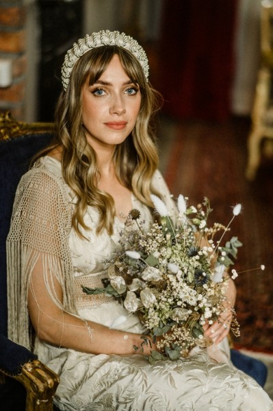 Bride looks to camera holding bouquet sitting down