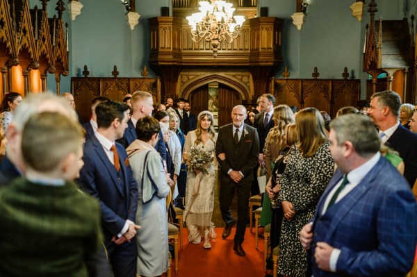 Father of the bride walks down the aisle guests watch