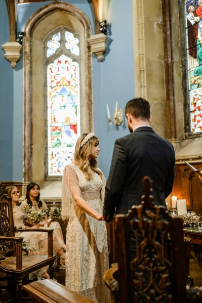 Bride and groom hold hands at alter