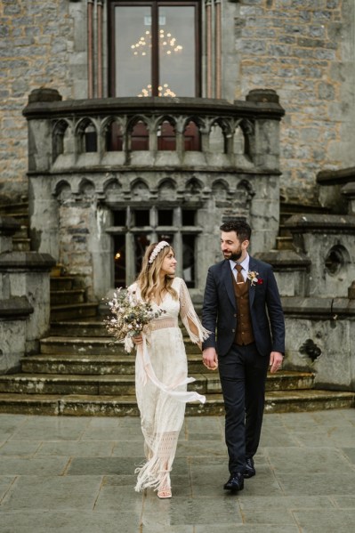 Bride and groom walk hand in hand holding hands outside wedding venue steps