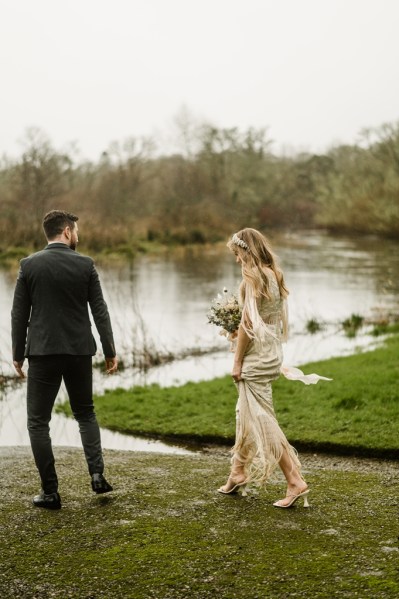 Bride and groom walk along lake setting pathway