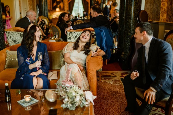 Woman sits on sofa laughing with guests