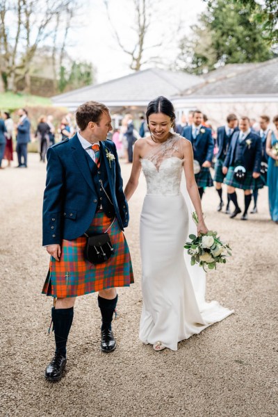 Bride and groom hand in hand holding hands smiling