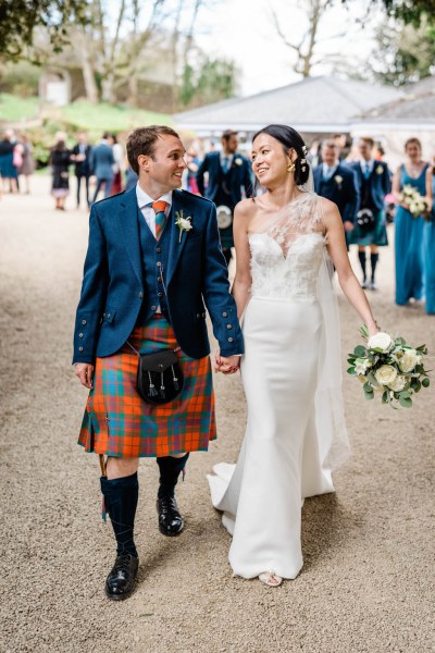 Bride and groom hand in hand look at each other