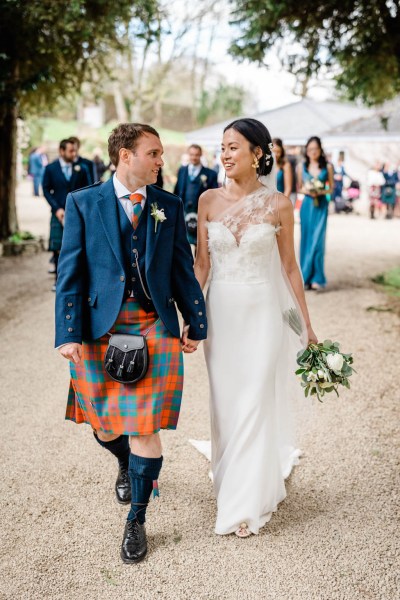 Bride and groom hand in hand look at each other