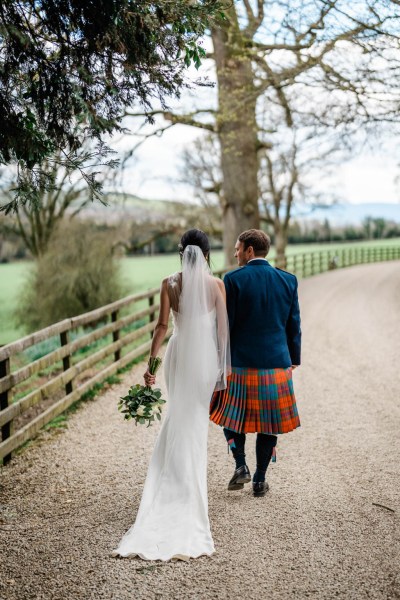 Bride and groom walk along pathway farm setting