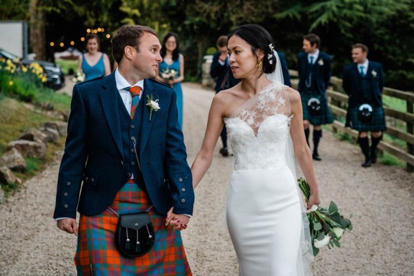 Bride and groom hand in hand holding hands look at each other