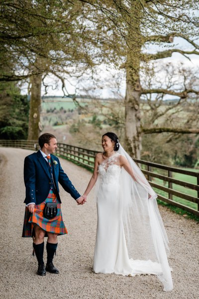 Bride and groom farm setting fence holding hands hand in hand trees surround couple