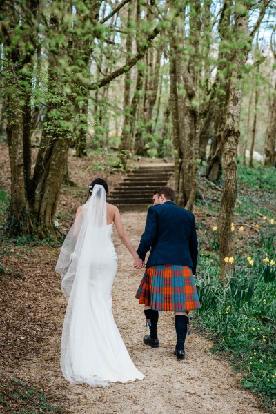 Bride and groom approach steps hand in hand holding hands