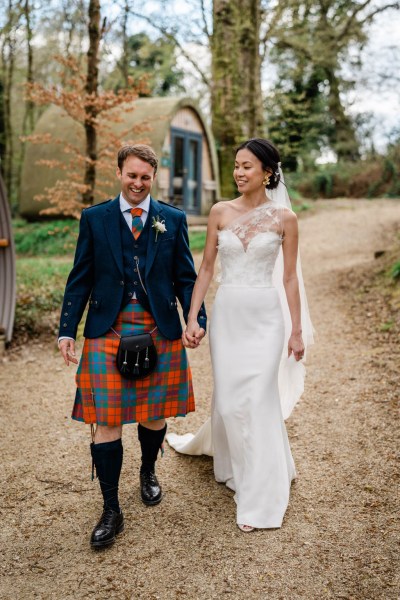 Bride shows off dress log cabins in background walking along pathway