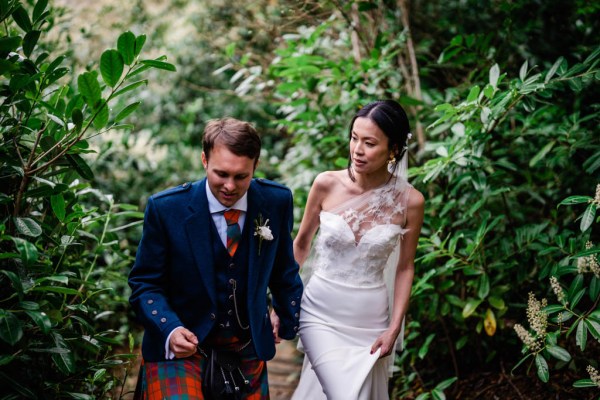 Bride and groom walk in forest hand in hand