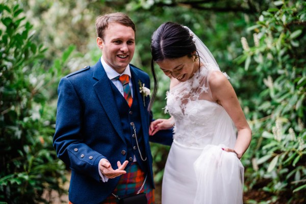 Bride and groom laugh together in forest setting