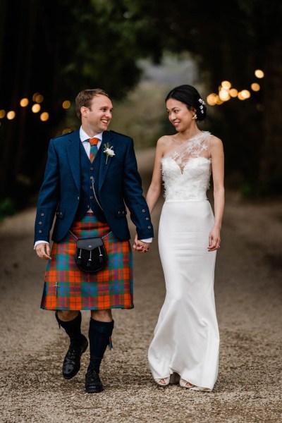 Couple bride and groom walk hand in hand smiling