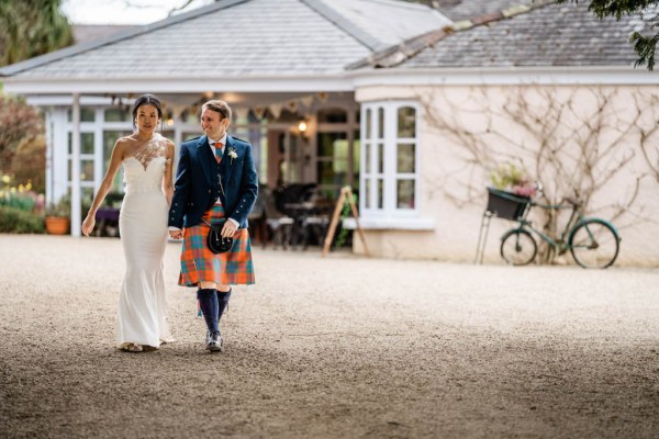 Bride and groom outside wedding venue holding hands