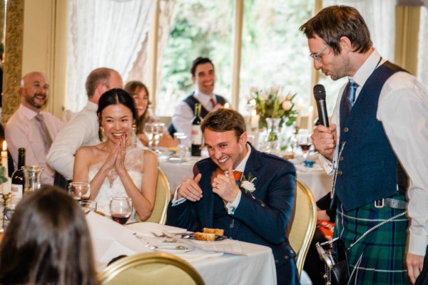 Bride and groom smiling laughing during speeches