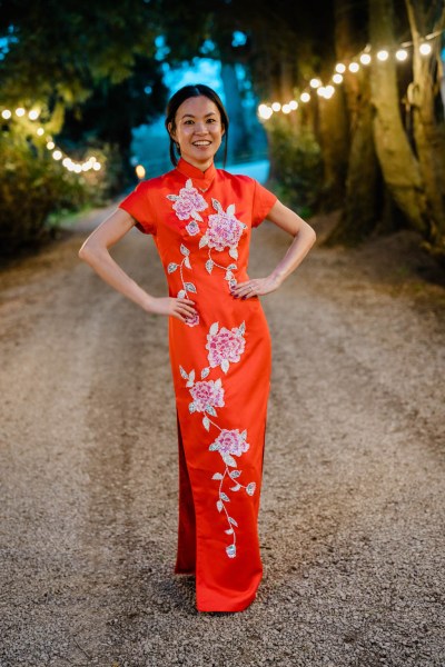 Bride poses in red floral dress along pathway