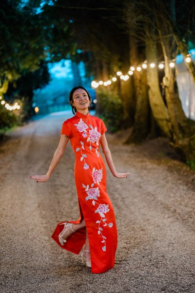 Bride poses in red floral dress along pathway