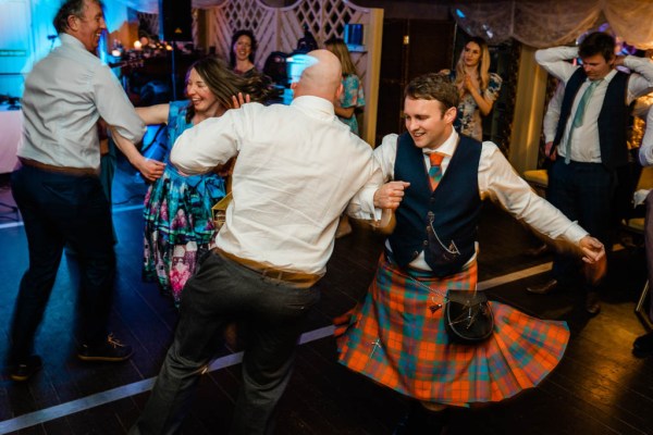 Groom dancing with man friend guest on dancefloor