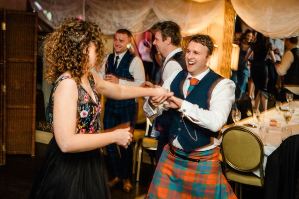 Groom in kilt dances with woman on dancefloor