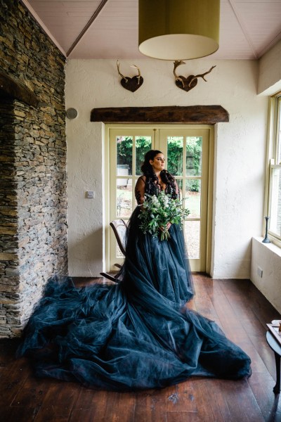 Bride on her own beside window holding flowers