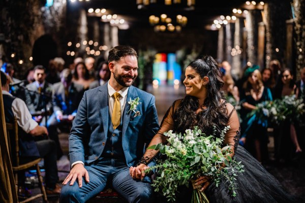 Bride and groom look at each other holding flowers in church