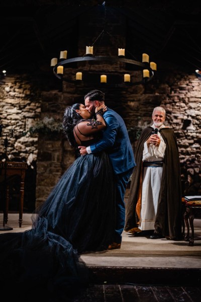 Bride and groom kiss in front of priest