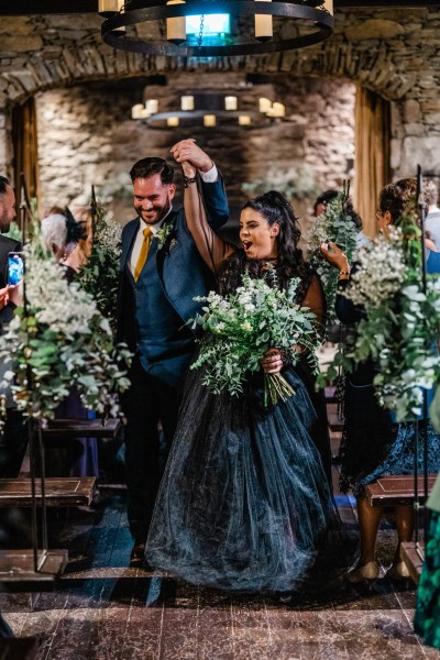 Bride and groom exit church hands in the air celebrate