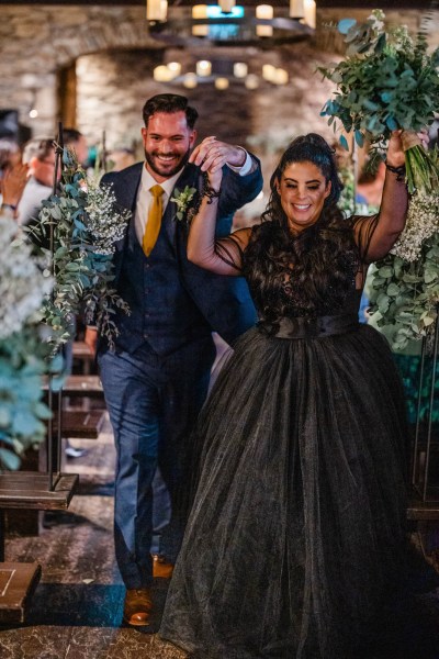 Bride and groom exit church hands in the air celebrate