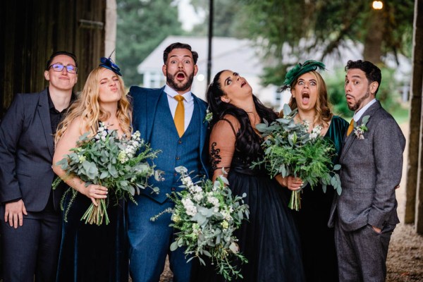 Bride and bridesmaid groom groomsmen pose for a photo in garden