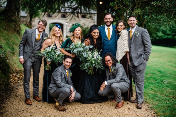 Bride groom groomsmen and bridesmaids in garden pathway bouquet trees