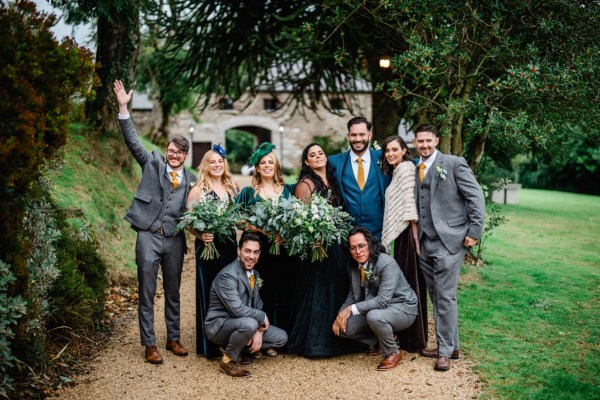 Bride groom groomsmen and bridesmaids in garden pathway bouquet