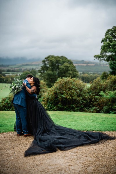 Bride and groom hug in front of farm setting mountains cliff