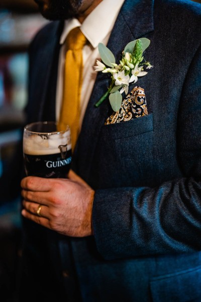 Groom drinks pint of Guinness suit and flower detail