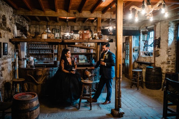 Bride and groom drink pints of Guinness in bar setting holding hands