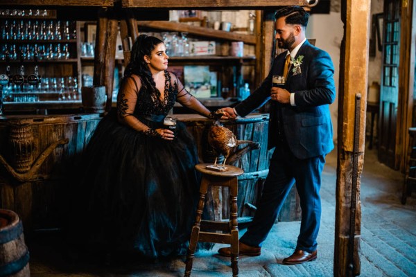 Bride and groom drink pints of Guinness in bar setting holding hands