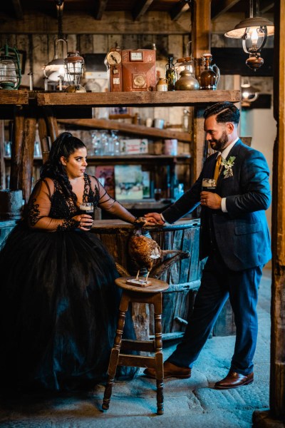 Bride and groom drink pints of Guinness in bar setting holding hands